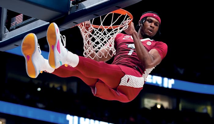 Arkansas guard Ricky Council looks down over Auburn defenders while his feet touch the backboard on a dunk.